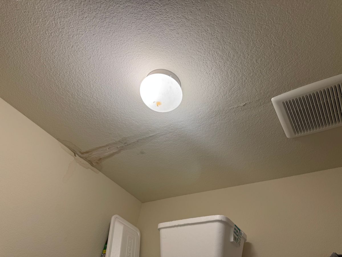 Before: a water stain and cracked seam running across a ceiling from the corner, next to the light and air vent