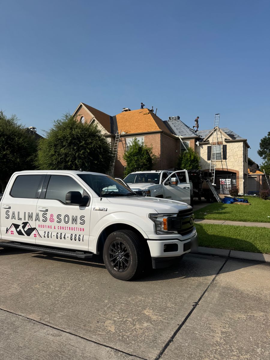 Crew tearing off the old roof on a Friendswood home, with tarps protecting the yard