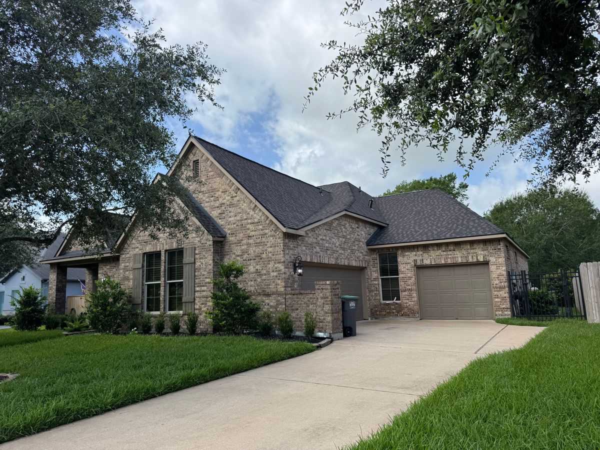 Finished roof on a brick home, with the driveway and yard left clean and clear of debris