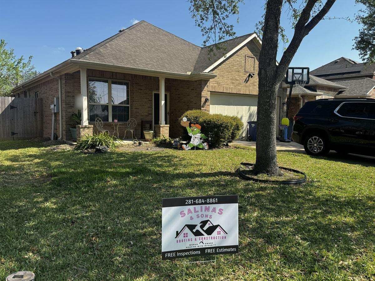 Brick home with an aging shingle roof and a Salinas and Sons yard sign in the front lawn, before work began
