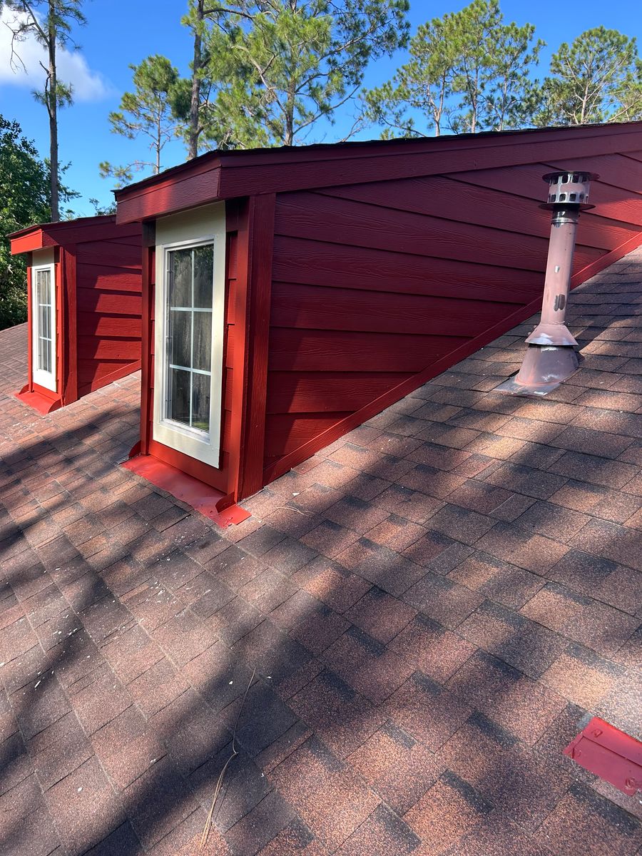 After: same dormer with rebuilt siding and freshly painted red trim