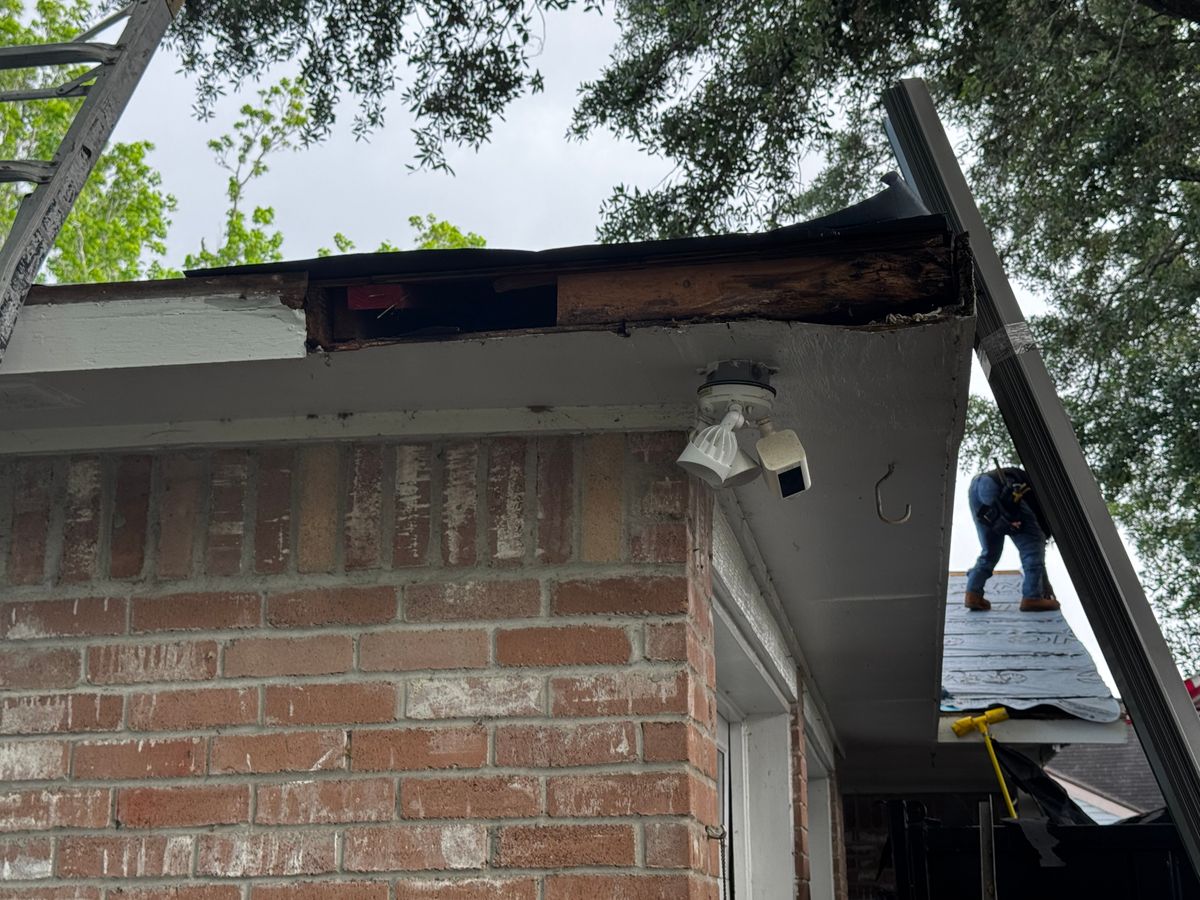 Before: rotted fascia board and open soffit along a brick home's roofline