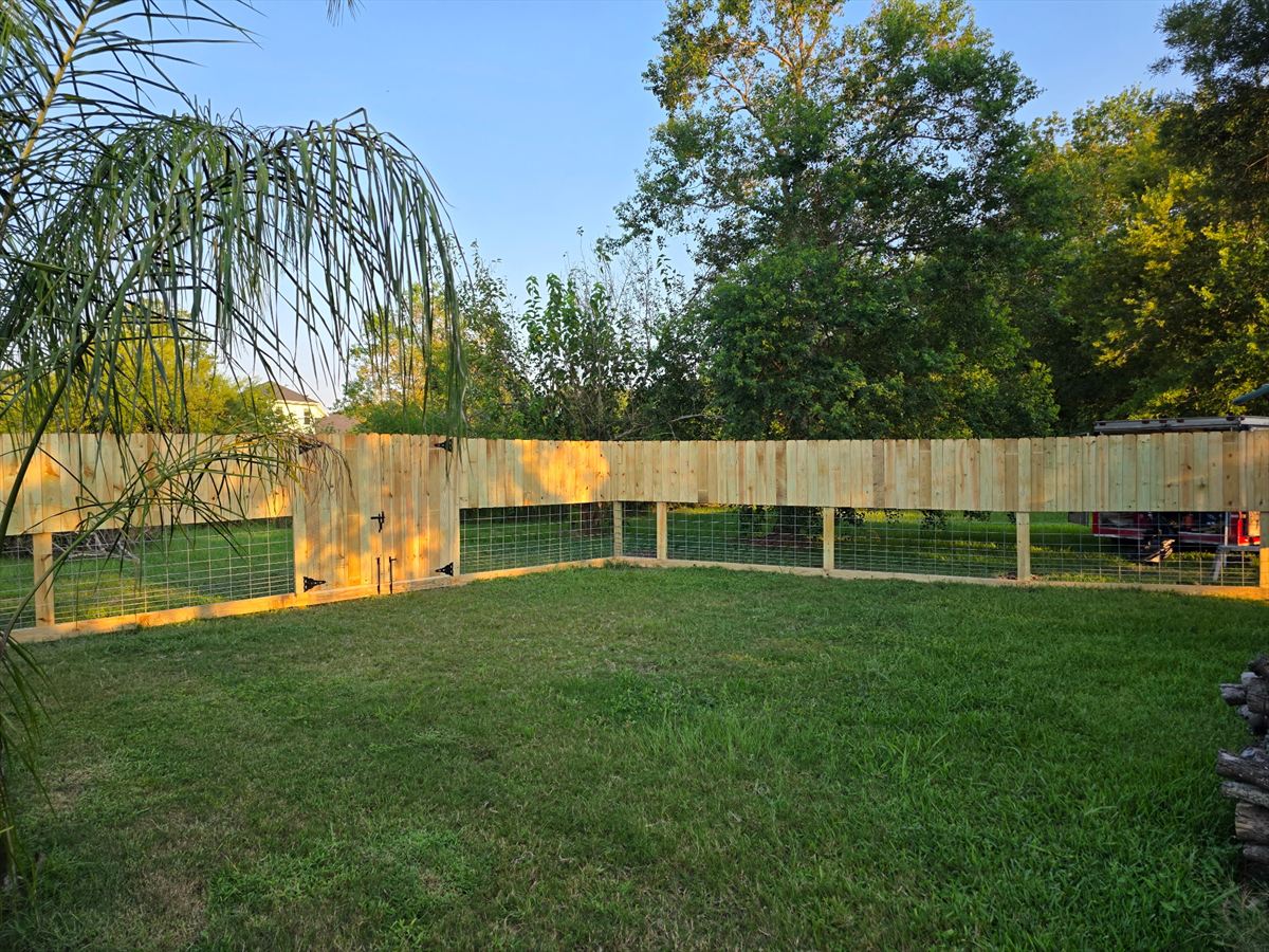 Completed wood privacy fence with no-climb wire mesh along the lower section, enclosing a back yard